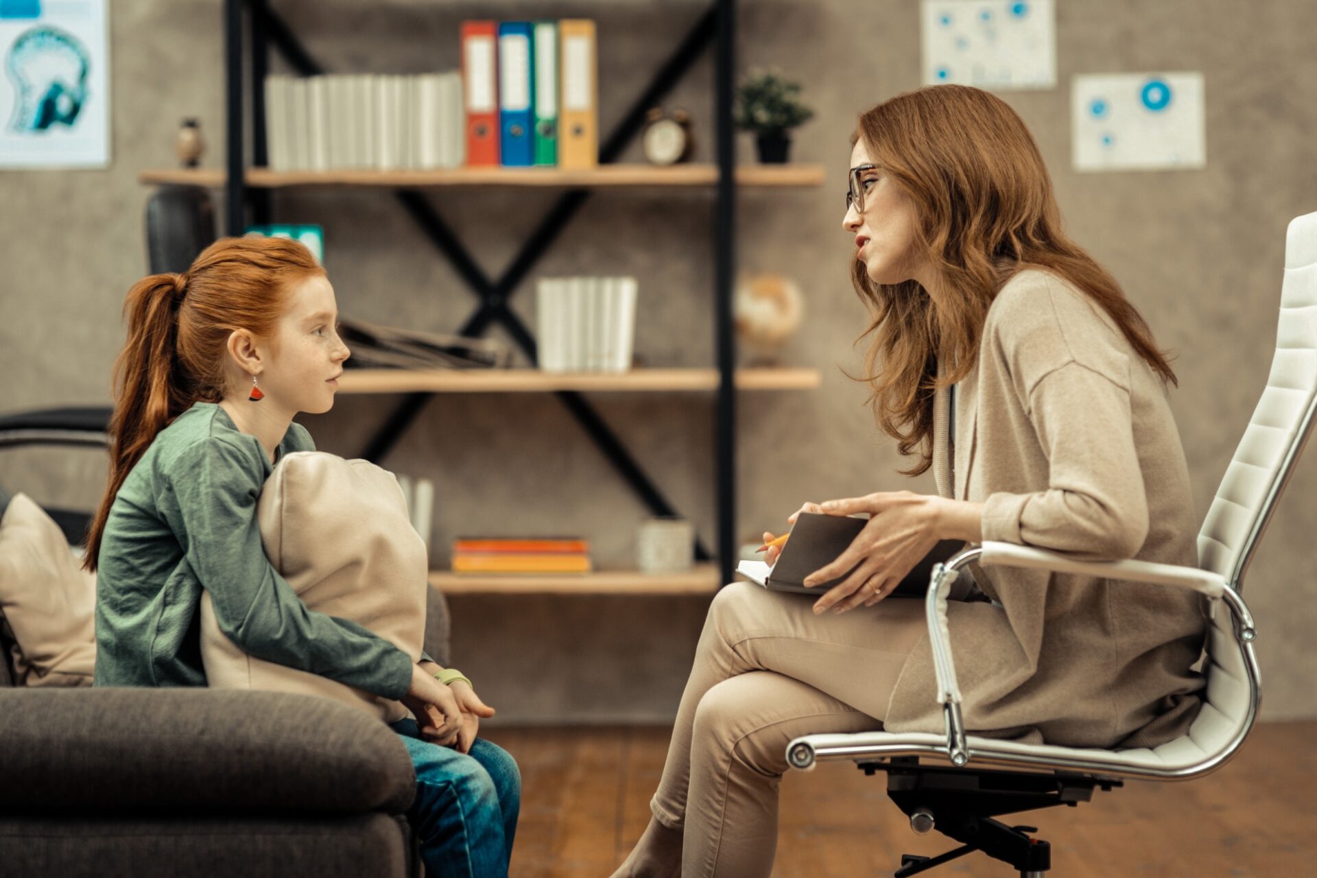 Young patient. Pleasant professional therapist holding her notes while speaking to her patient Young patient. Pleasant professional therapist holding her notes while speaking to her patient